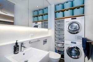 uma casa de banho com um lavatório e uma máquina de lavar roupa em Serenity in the City - 1BD Studio Wifi CBD em Adelaide