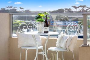 a table with a bottle of wine and chairs on a balcony at Salt Five Apartment Sorrento - Main Street Location in Sorrento