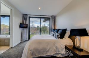 a bedroom with a large bed and a large window at Terrace Lodge by Sotheby's Luxury Rental Homes in Queenstown