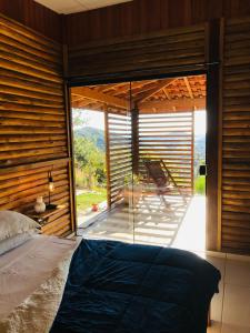 1 dormitorio con 1 cama y una gran ventana de cristal en Chalé do Vale locação de temporada, en Águas de Lindóia