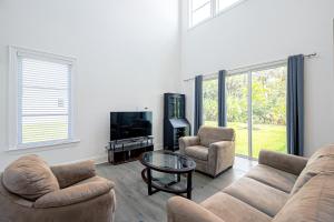 a living room with a couch and two chairs and a tv at Ocean Estate in Fort Pierce