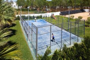 two people playing tennis on a tennis court at Alcazar Hotel & SPA in Monte Gordo