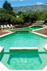 a swimming pool with green water and chairs in it at Rincón de los Troncos in Merlo