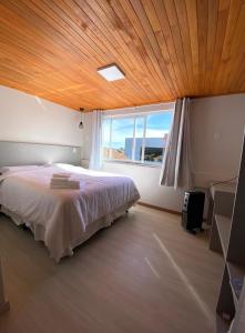 1 dormitorio con 1 cama grande y techo de madera en Loft na Serra Catarinense en São Joaquim