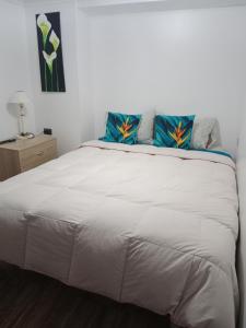 um quarto com uma grande cama branca com almofadas azuis em Tu Jardín Secreto em La Serena