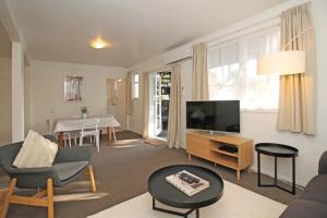 un soggiorno con TV e tavolo di 2 Bed Apartment in Kingsland - FREE WIFI and parking ad Auckland