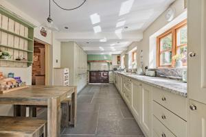 een grote keuken met witte kasten en een houten tafel bij The Cottage, Beautiful New Forest 5 Bedroom Thatched Cottage in Breamore