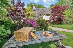a picnic table with a basket and vegetables on it at The Cottage, Beautiful New Forest 5 Bedroom Thatched Cottage in Breamore