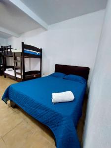 Un dormitorio con una cama azul con una toalla blanca. en Restaurante y cabinas Sudy, en Carara