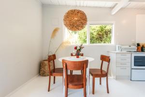 a kitchen with a table and chairs and a window at Onetangi Waterfront Bach - Coast & Country in Onetangi