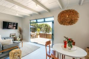 a living room with a table and a couch at Onetangi Waterfront Bach - Coast & Country in Onetangi