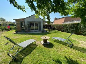 duas cadeiras e uma mesa num quintal com uma casa em Charming holiday home in a quiet location, near the coast, 2 bicycles em Donville-les-Bains