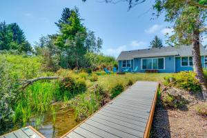 a blue house with a wooden walkway in front of a yard at Canal Cottage Retreat with Dock and Waterfront Views in Ocean Shores
