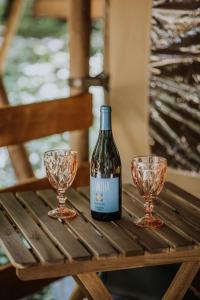 Sioglamping in Siocamping في سيوفوك: زجاجة من النبيذ وكأسين على طاولة خشبية