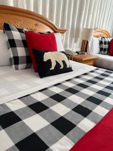 a bed with a black and white checkered blanket with a bear pillow at Mystic Isle Motel in Wawa