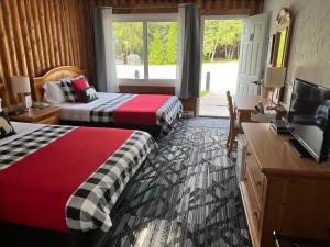 una camera d'albergo con 2 letti, una scrivania e una TV di Mystic Isle Motel a Wawa