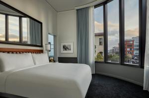 a bedroom with a large white bed and large windows at Pendry San Diego in San Diego