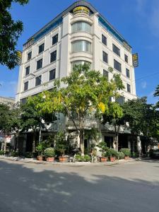 a large white building with trees in front of it at Golden Thai binh Hotel in Thái Bình