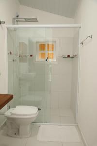 a white bathroom with a shower and a toilet at Casa do Papai in Campos do Jordão