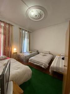 um quarto com 3 camas e um piso verde em Lisbon Bangla em Lisboa