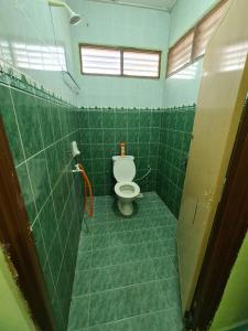 a bathroom with a toilet in a green tiled room at Penginapan Harmoni Inn in Kuala Terengganu