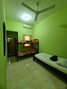 a green room with two bunk beds and a fan at Penginapan Harmoni Inn in Kuala Terengganu