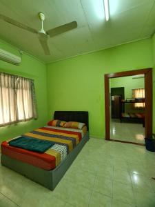 a green bedroom with a bed and a mirror at Penginapan Harmoni Inn in Kuala Terengganu
