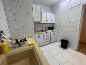 cocina de azulejos blancos con fregadero y bañera en Hakimdom Hostel, en Riad
