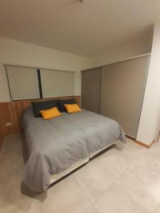 1 dormitorio con 1 cama con 2 almohadas de color naranja en Aire de Chapelco en San Martín de los Andes