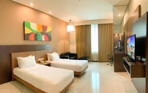 a hotel room with two beds and a flat screen tv at Savana Hotel & Convention Malang in Malang