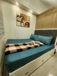 ein Schlafzimmer mit einem Bett mit einer karierten Decke in der Unterkunft Skyia's Pod a Premier Suite at Shore 2 Residences in Manila