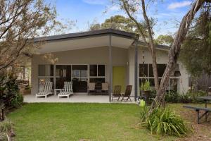 a house with a porch with chairs and a patio at Woodland Retreat in Cowes