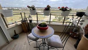 un balcón con una mesa con una maceta. en Nouaceur Garden, en Casablanca