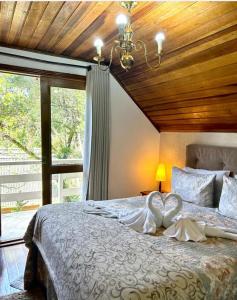 1 dormitorio con 1 cama grande y techo de madera en Casa do Papai, en Campos do Jordão