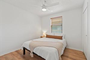 a white bedroom with a bed and a window at Spacious Home Near Beach, Large Yard, Game Room and Dog Friendly in Jacksonville