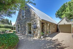 a stone house with a garage and a barn at Quigtoo Cottage in Berridale