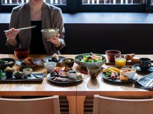 une femme assise à une table avec des assiettes de nourriture dans l'établissement Mitsui Garden Hotel Kyoto Shinmachi Bettei, à Kyoto