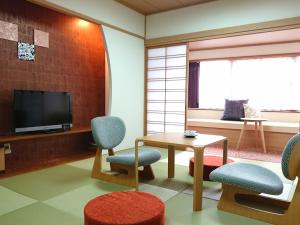 een kamer met 2 stoelen, een tafel en een tv bij Hanayuzuki in Matsuyama
