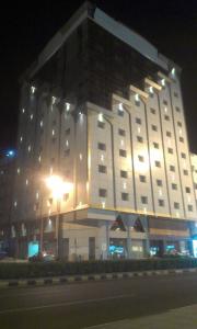 a large white building at night with a street at Athman Hotel in Makkah