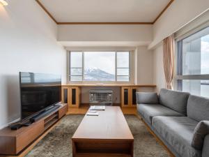 a living room with a couch and a flat screen tv at Mountainside Palace in Niseko