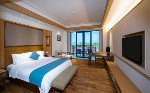 um quarto com uma cama grande e uma televisão de ecrã plano em HNTI·Narada Sanya Bay Resort em Sanya