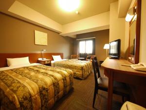 網走市にあるホテルルートイン網走駅前のベッド2台とデスクが備わるホテルルームです。