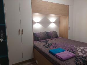 een kleine slaapkamer met een bed met paarse lakens bij Lux Apartment with Large Balcony in Skopje