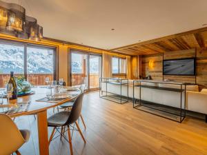 ein Esszimmer mit Tisch und Stühlen und einem Fernseher in der Unterkunft Duplex Spacieux au Rond-Point des Pistes avec Parking, Balcon et Services Inclus - FR-1-613-93 in Les Allues + 13 Fotos