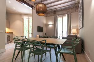 ein Esszimmer mit einem Holztisch und grünen Stühlen in der Unterkunft Weflating Suites Sant Antoni Market in Barcelona