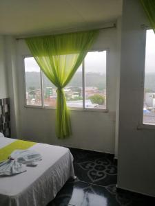 ein Schlafzimmer mit einem grünen Vorhang und einem Fenster in der Unterkunft Hotel Luis Ángel in Mocoa