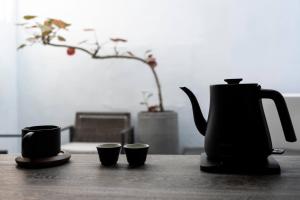 a coffee pot and three cups on a table at Sukinab&b喜歡旅居曲巷冬晴 in Lugang