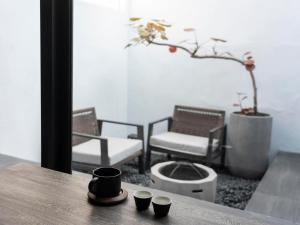 einen Tisch mit drei Tassen auf einem Tisch mit Stühlen in der Unterkunft Sukinab&b喜歡旅居曲巷冬晴 in Lukang