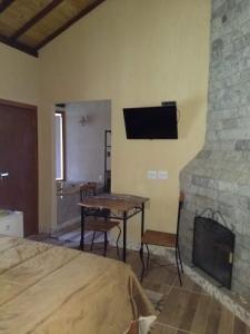 a bedroom with a fireplace and a bed and a table at Chalés das Orquídeas in Visconde De Maua