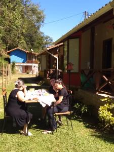 a group of women sitting at a table in a yard at Chalés das Orquídeas in Visconde De Maua
